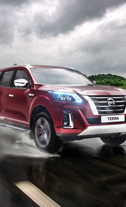 Red Nissan Terra driving on a wet tar road